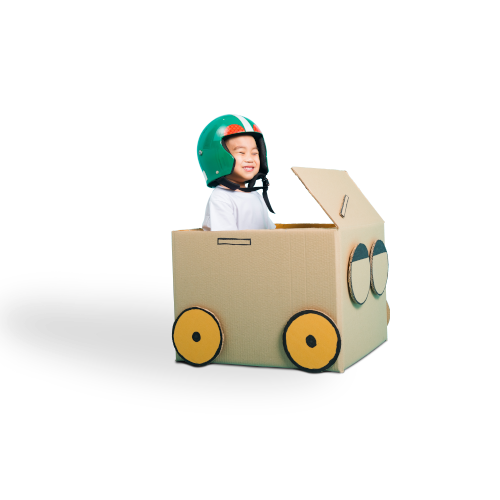 Smiling boy wearing a helmet in cardboard box that is decorated as a car.